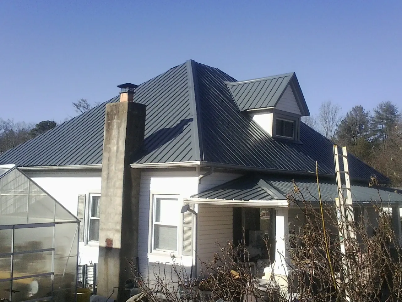 Dark blue standing seam metal roof on a white farmhouse with dormer — Slate & Tile Roof Repair by Roofing Brothers in Eatonton