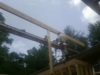 Carpenter setting a ridge beam over a new addition frame — Ice Dam Removal by Roofing Brothers in Eatonton
