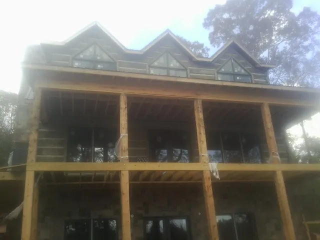 Dormers and porch framing on a large log home under construction — Roof Coating work by our crew in Eatonton