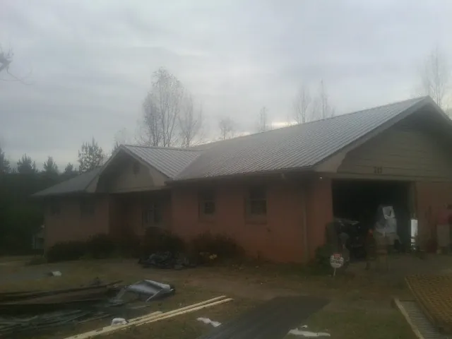 Gray metal roof on a stucco house with an attached garage in Eatonton