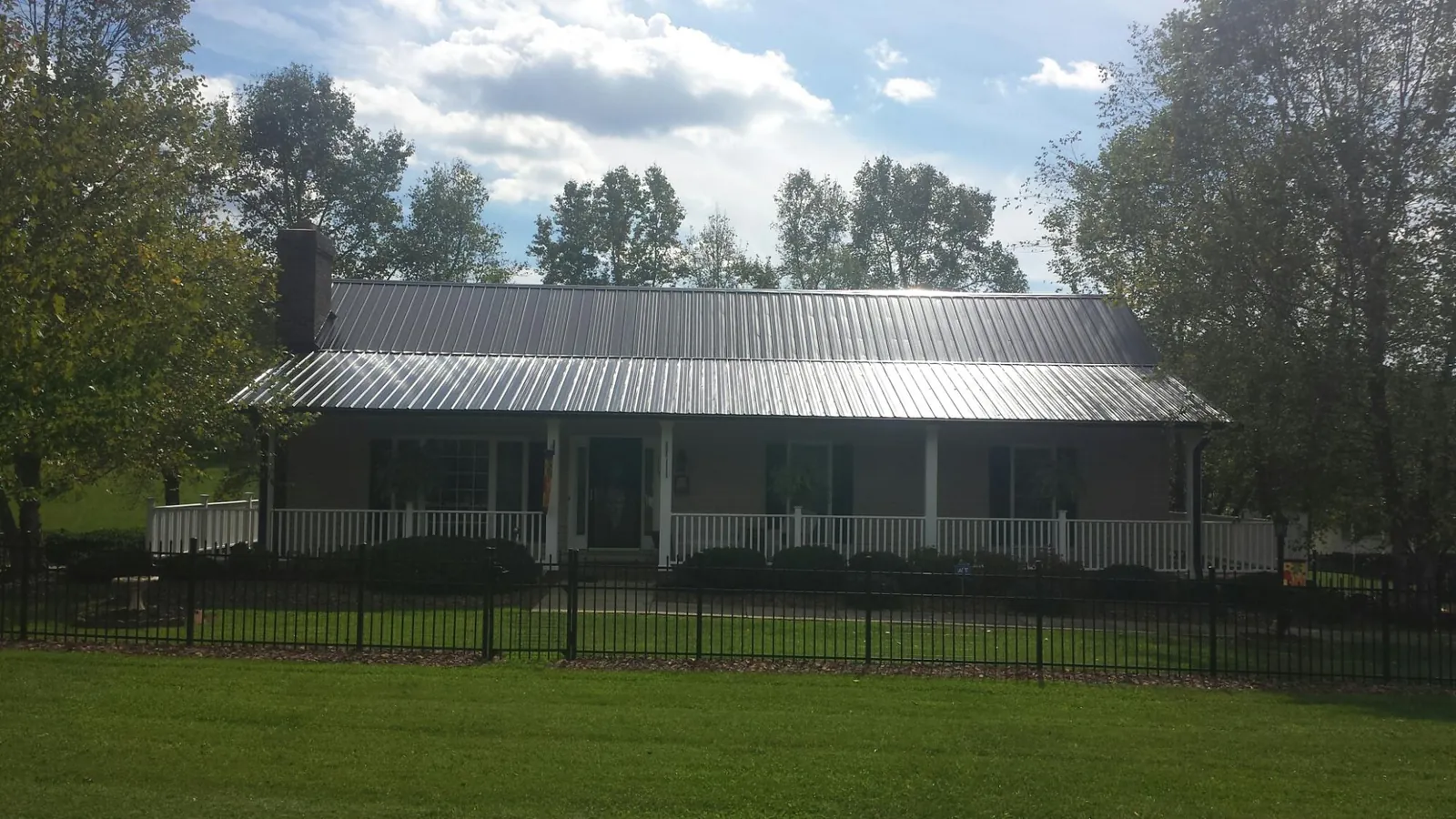 Gray metal roof on a brick ranch with a full width front porch — Gutter Guard Installation work by our crew in Eatonton