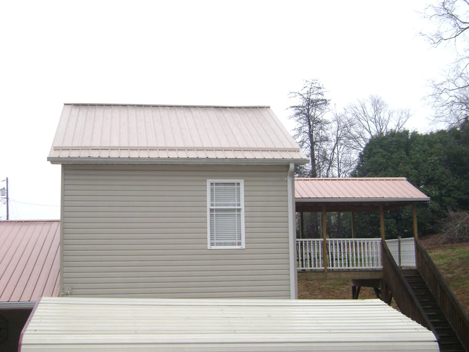 Tan metal roofs on a two story addition and attached porch, from a Roof Replacement job in Eatonton