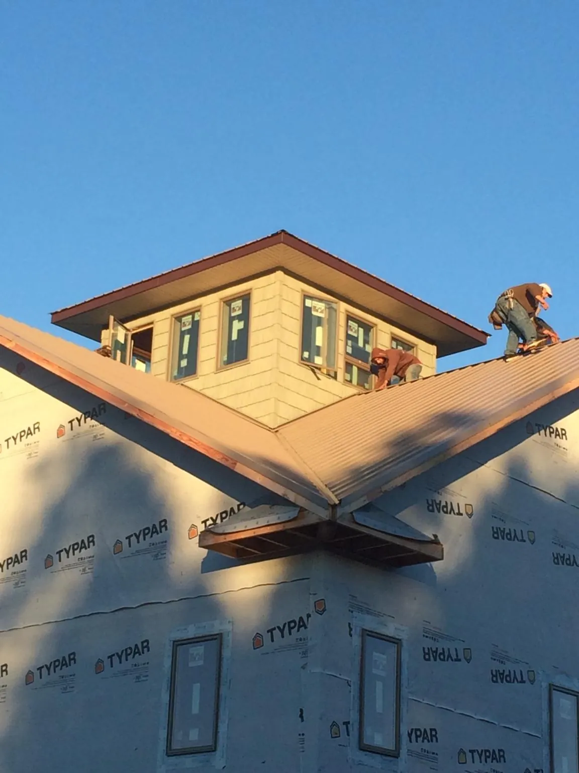 Roofers working around a rooftop cupola on a new metal roof at sunset — Roof Waterproofing in Eatonton by Roofing Brothers
